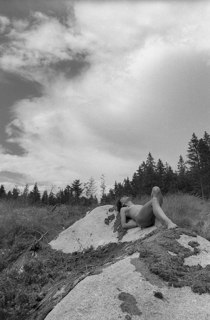 Femme nue allongée sur un rocher en forêt
