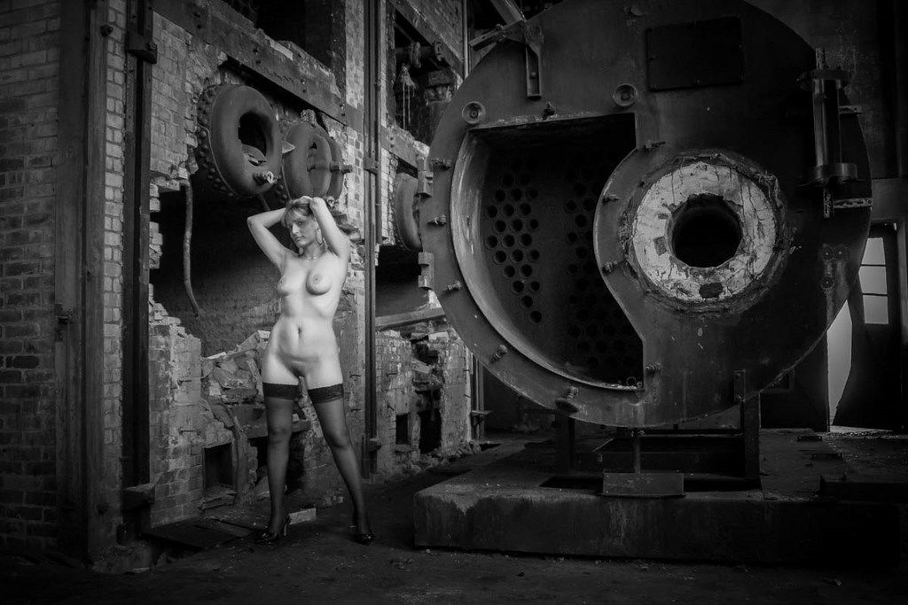 Femme nue debout devant une vieille chaudière