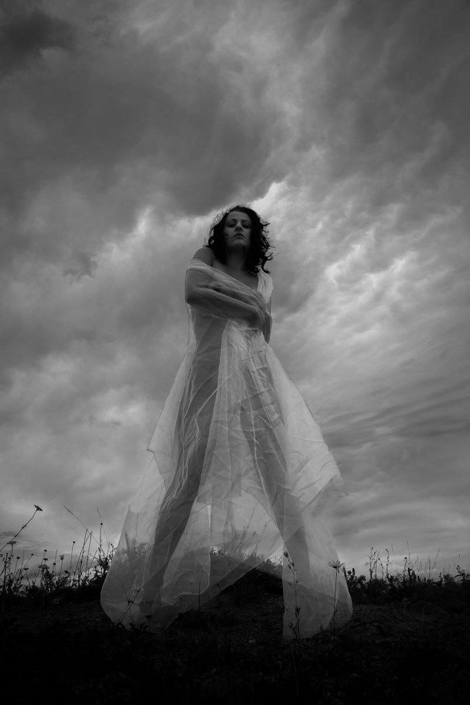 Femme habillée d'un voile blanc sous un ciel menaçant