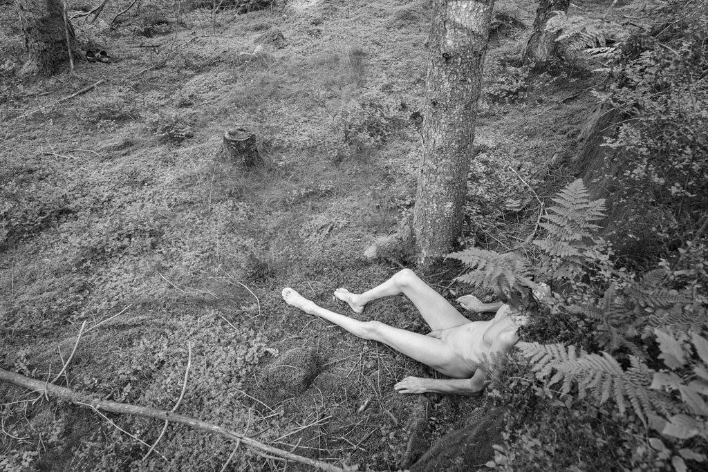 Homme nu assis dans la mousse de la forêt