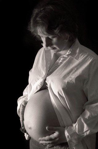 Femme enceinte avec la chemise ouverte sur ventre rond