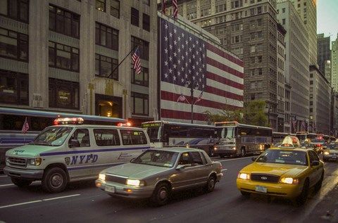 Un Taxi jaune, un véhicule de police et le drapeau américain dans les rues de New-York
