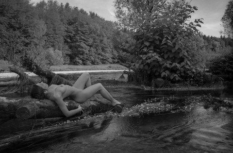 Femme nue allongée sur un tronc d'arbre dans l'eau