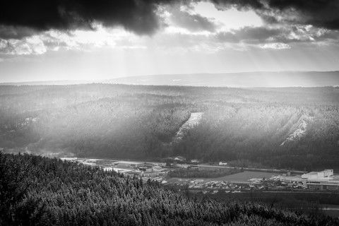 nuages menaçants laissant passer des rayons de lumières sur la forêt