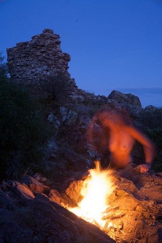 Femme nue, dansant derrière un feu dans des ruines d'un château