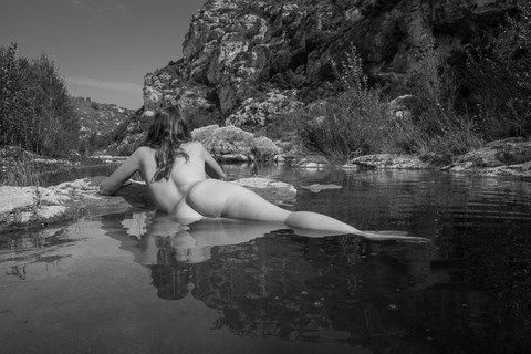 Femme nue, allongée sur le ventre dans une rivière