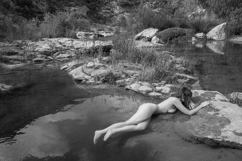 Femme nue, allongée dans une rivière